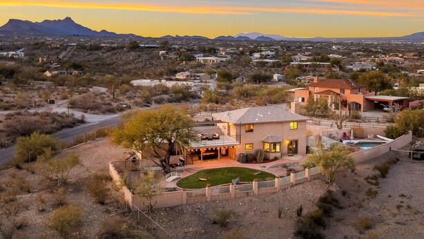 A residential area with a house featuring a patio, swimming pool, and a view of distant mountains.