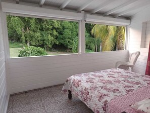 Une chambre avec un lit, une chaise et une fenêtre donnant sur un paysage verdoyant.