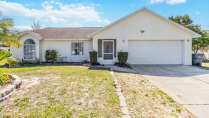 A single-story house with a garage, a front yard with a small garden, and a clear blue sky. - 5/3 Vacation home with a large pool near the Disney attractions!! (Davenport)