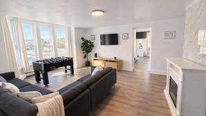 Ett vardagsrum med en soffa, ett fotbollsspel, en tv och en öppen spis.