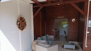 A covered patio area with a wicker sofa, a small table, and a decorative wall hanging.