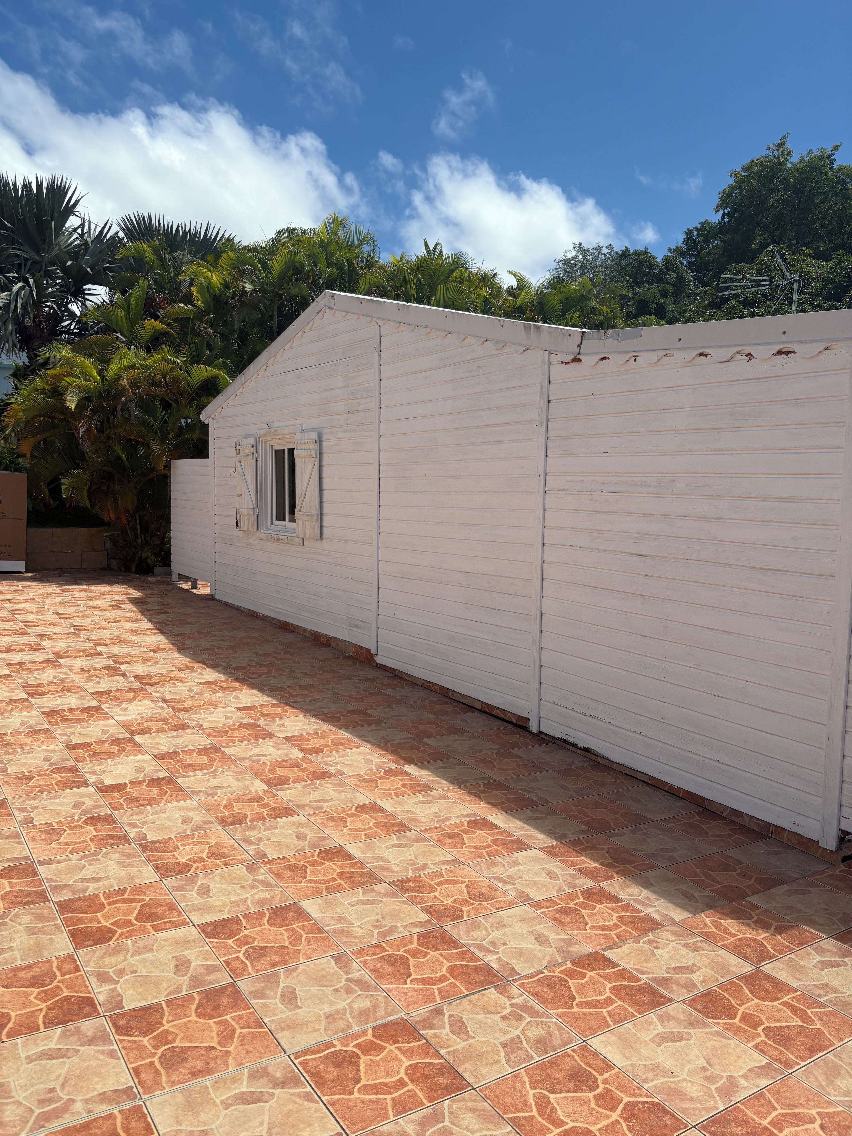 Un edificio blanco con una ventana, junto a un patio con baldosas.