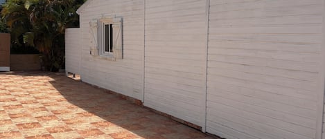 A white building with a window, adjacent to a tiled patio area.