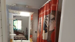 A bathroom with a white sink, mirror, and cabinet. There is a red shower curtain with a leaf pattern.