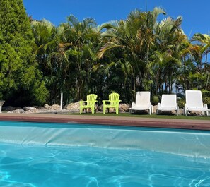 A swimming pool with clear blue water, surrounded by palm trees and lounge chairs. - La Palmeraie (formerly Maison Hator) in Grand-Bourg (Grand-Bourg)