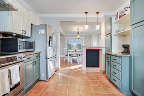 Enjoy cooking in this kitchen with stainless steel appliances, a microwave, oven, and refrigerator, and dining area with a table and chairs.