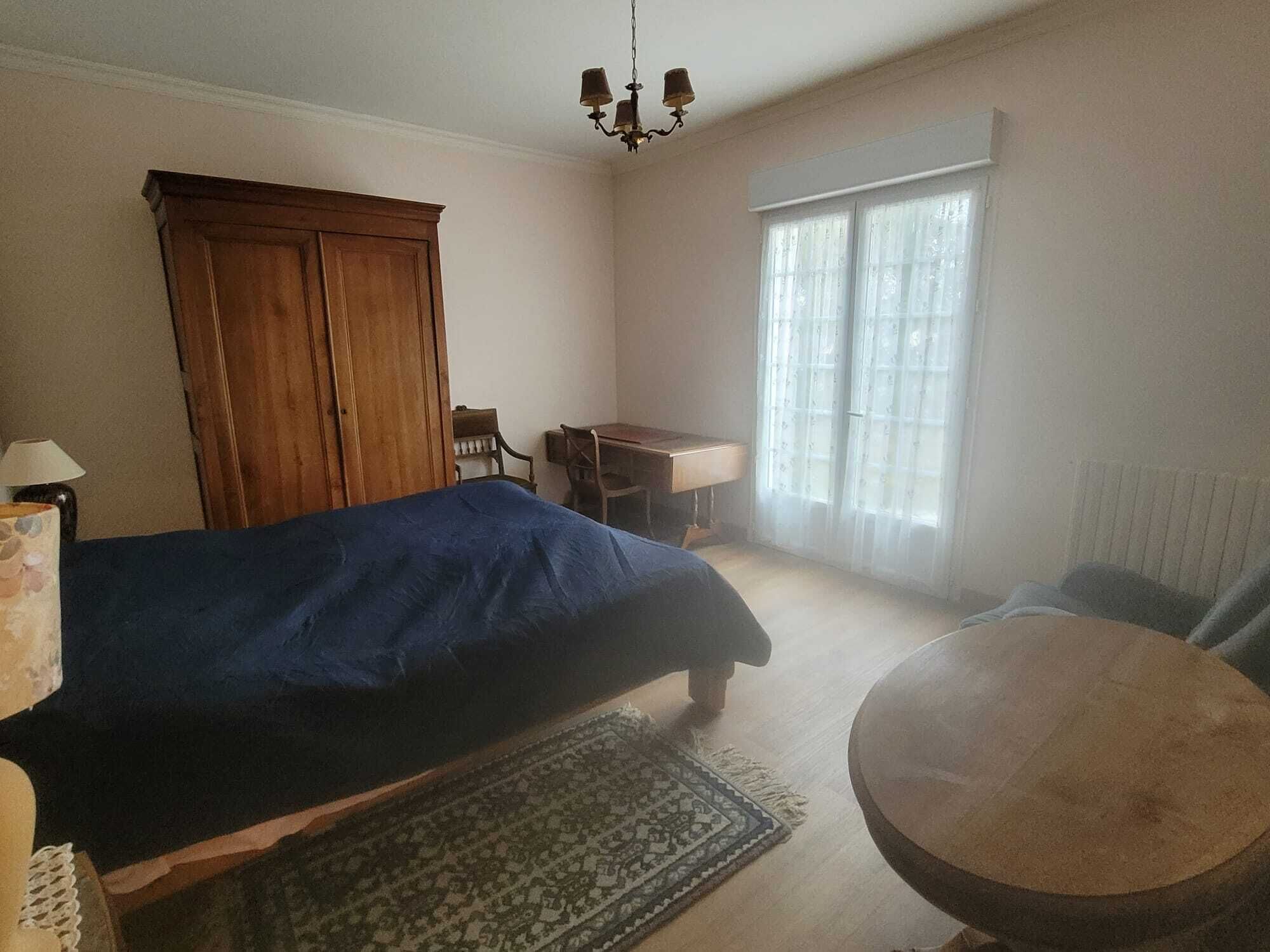 Un dormitori amb un llit, escriptori, cadira, taula rodona i un armari.