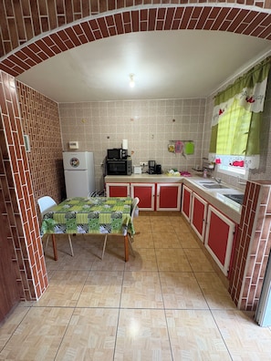 Cocina compacta con una mesa de comedor, refrigerador, microondas y cafetera.