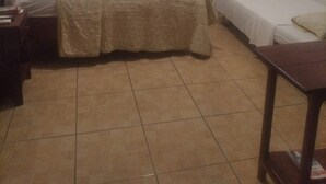 A small, dimly lit room with two beds, a wooden nightstand, and a small table.