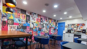 A lounge with tables and chairs, a colorful wall, and a blue door.