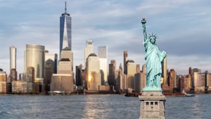 The Statue of Liberty in front of a city skyline with buildings in the background.