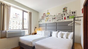 A hotel room with two beds, a large window with curtains, an air conditioning unit, and a cityscape mural on the wall. - Cozy hotel in Soho - 2 Double Beds (New York)