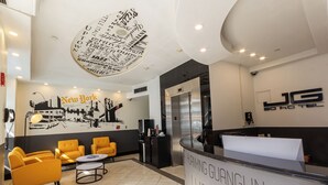 A hotel reception area with a modern design, featuring a reception desk, seating area with yellow chairs, and a wall with a New York City mural. - Cozy hotel in Soho - 2 Double Beds (New York)