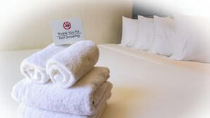 A neatly made bed with white linens and a sign thanking guests for not smoking. - Cozy hotel in Soho - 2 Double Beds (New York)