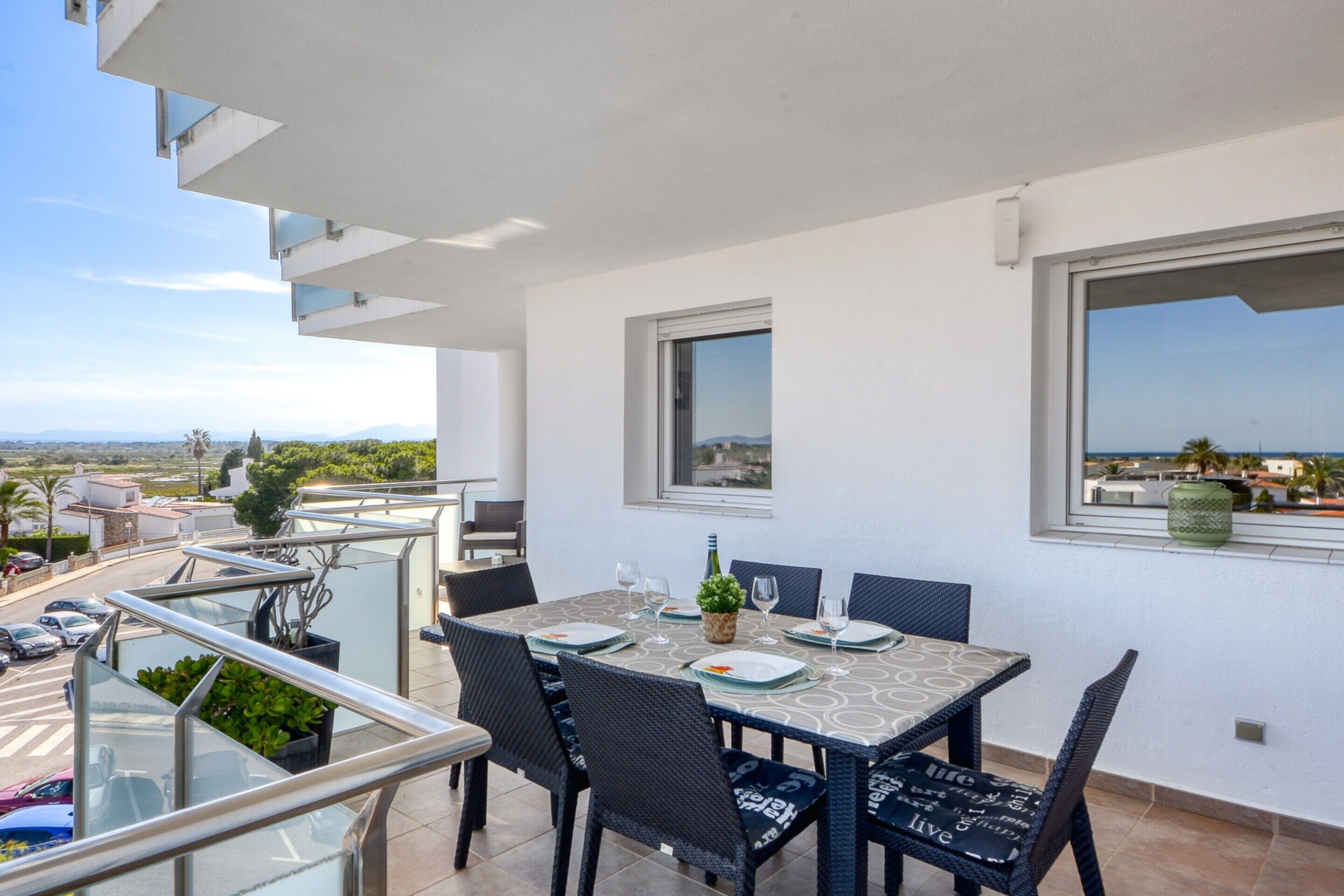 A balcony with a dining table set for four, surrounded by wicker chairs.