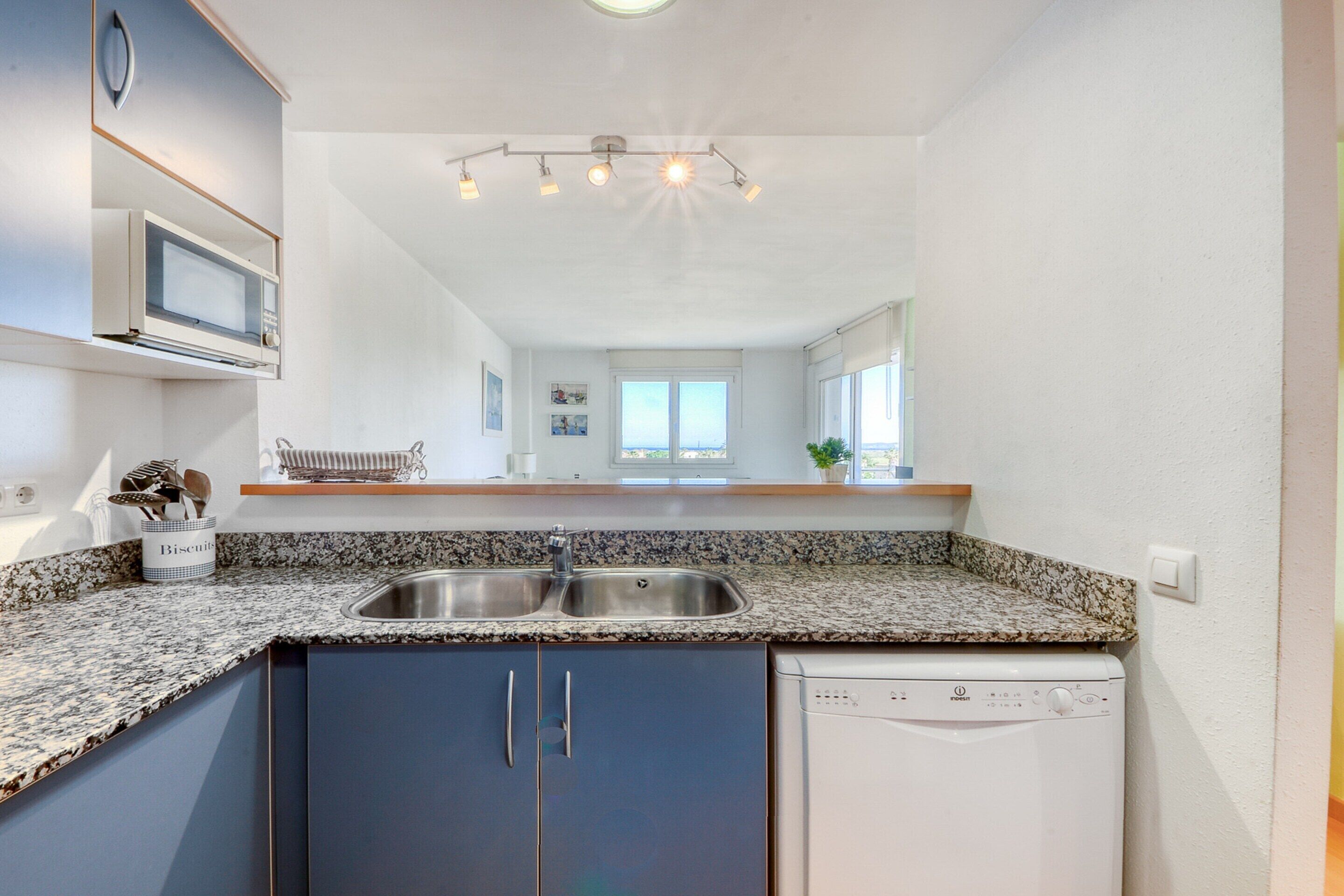 A modern kitchen with a double sink, built-in microwave, and a dishwasher.