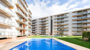 Een modern appartementencomplex met een zwembad, balkons en een verzorgd gazon.
