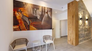 Decoração moderna com uma grande pintura abstrata, duas cadeiras de vime e uma parede de detalhes em madeira.