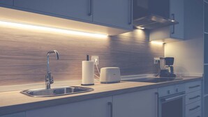 Uma cozinha moderna com uma pia de aço inoxidável, uma cafeteira e um rolo de papel toalha.