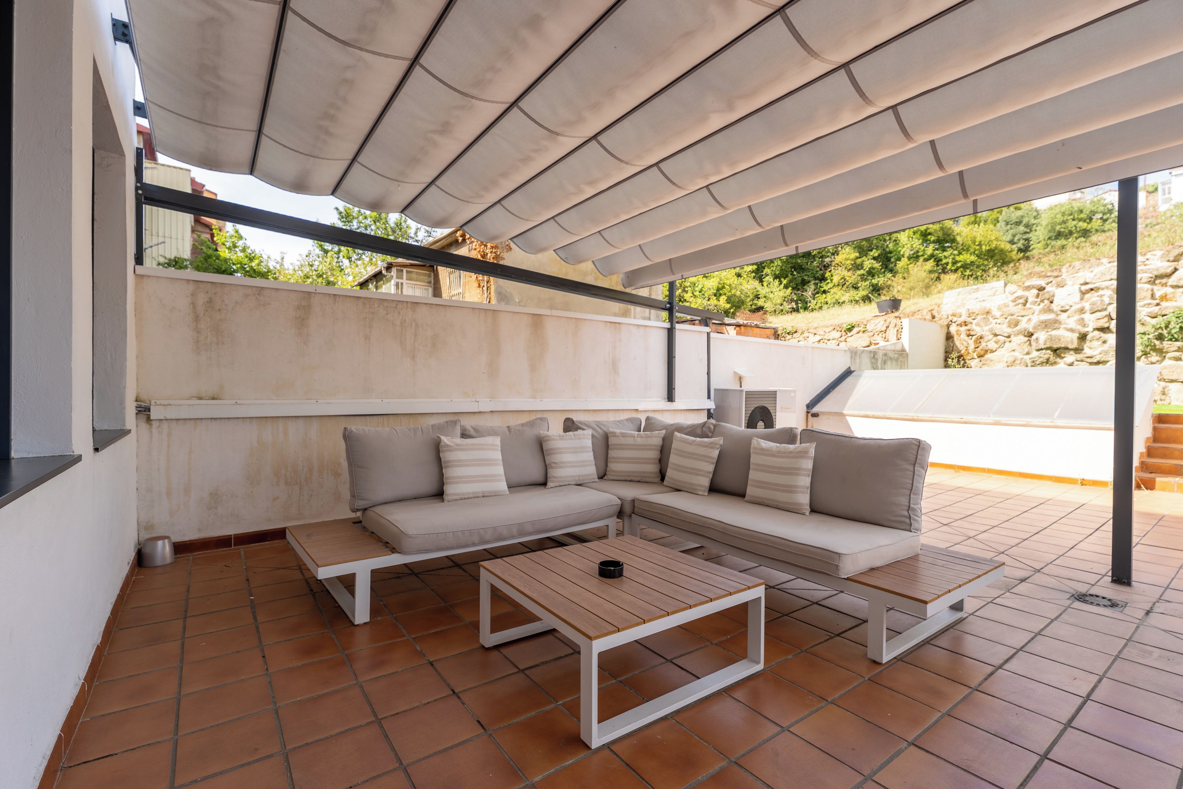 Un espacio de estar al aire libre con techo, un sofá y una mesa.