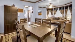 Un salón amplio con una gran mesa de madera para comer, asientos cómodos y un ventilador de techo.