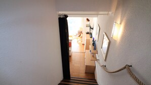 Una escalera conduce a una habitación con una cama, un escritorio y una ventana.