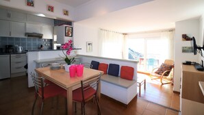 Una cocina moderna con armarios blancos, una mesa de comedor con sillas rojas y un banco empotrado con cojines rojos.