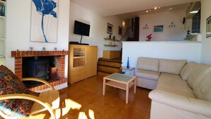 Una sala de estar con chimenea, un sofá, un televisor y una escalera que lleva a un nivel superior.