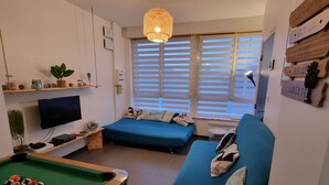 A compact living space with a pool table, a sofa, and a television.