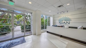 A reception area with a glass door leading outside, a reception desk, and a logo for SIAN Ocean Residences on the wall.