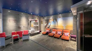 A spa room with a stone floor, a large mural of a beach scene, and multiple orange chairs.