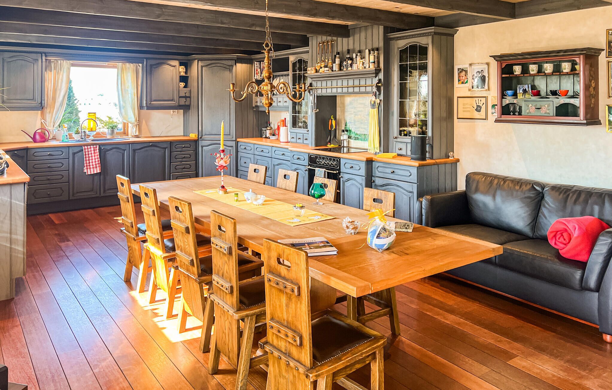 A spacious kitchen with wooden cabinetry, a dining table, and a sofa.