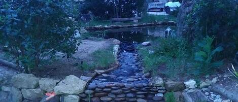 A garden with a small stream, surrounded by rocks and plants.