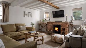 Un salon confortable avec une cheminée, un canapé, une table basse et un téléviseur.