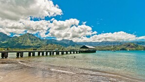 A pier extending into a clear blue sea with mountains in the background. - New Deluxe A/C Home, Spectacular Mountains Views (Princeville)