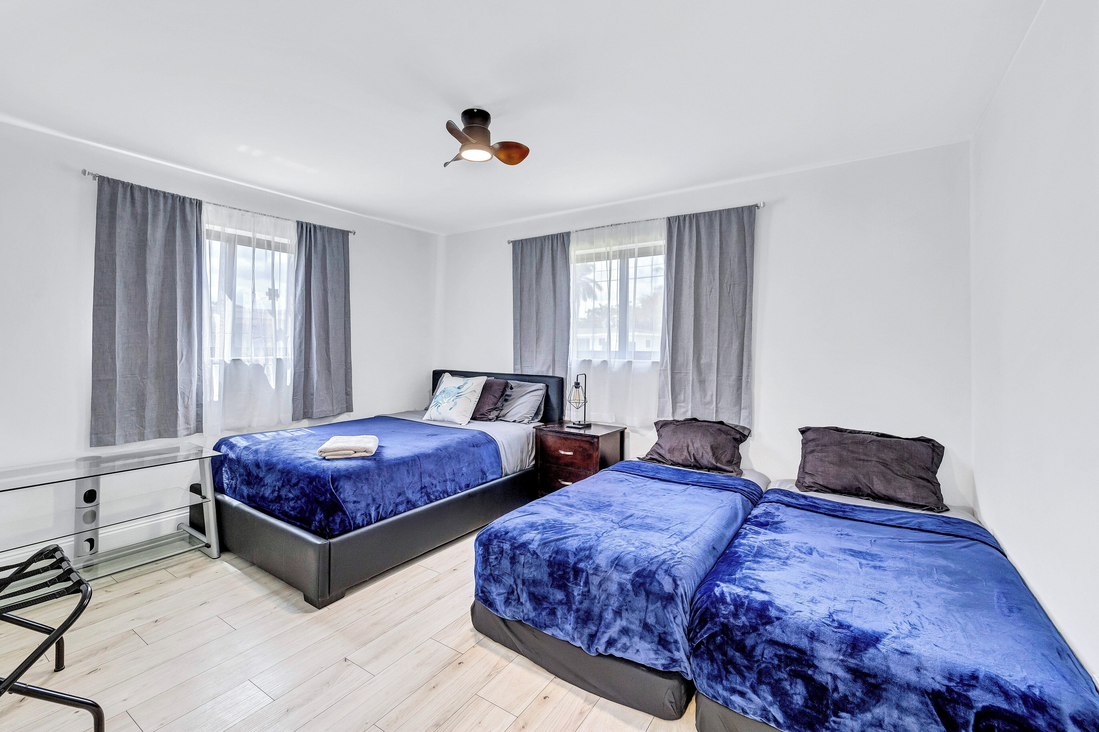 A modern hotel room with two beds, a desk, and a ceiling fan.