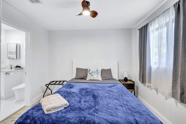 Een moderne slaapkamer met een groot bed, een nachtkastje, een spiegel en een raam met gordijnen.