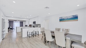 A modern kitchen with a marble countertop and a dining area with a large island and upholstered chairs.