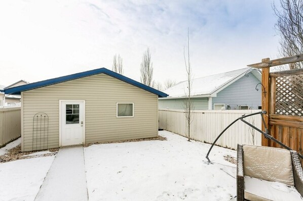A single-story house with a blue roof, a small attached garage, and a fenced backyard.