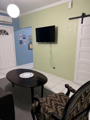Relax in a stylish space with a flat-screen TV, round table, and comfortable armchair.
