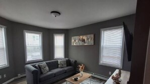 A living room with a gray sofa, a coffee table, and a painting on the wall.