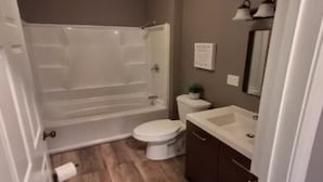 A bathroom with a bathtub, toilet, sink, and mirror.