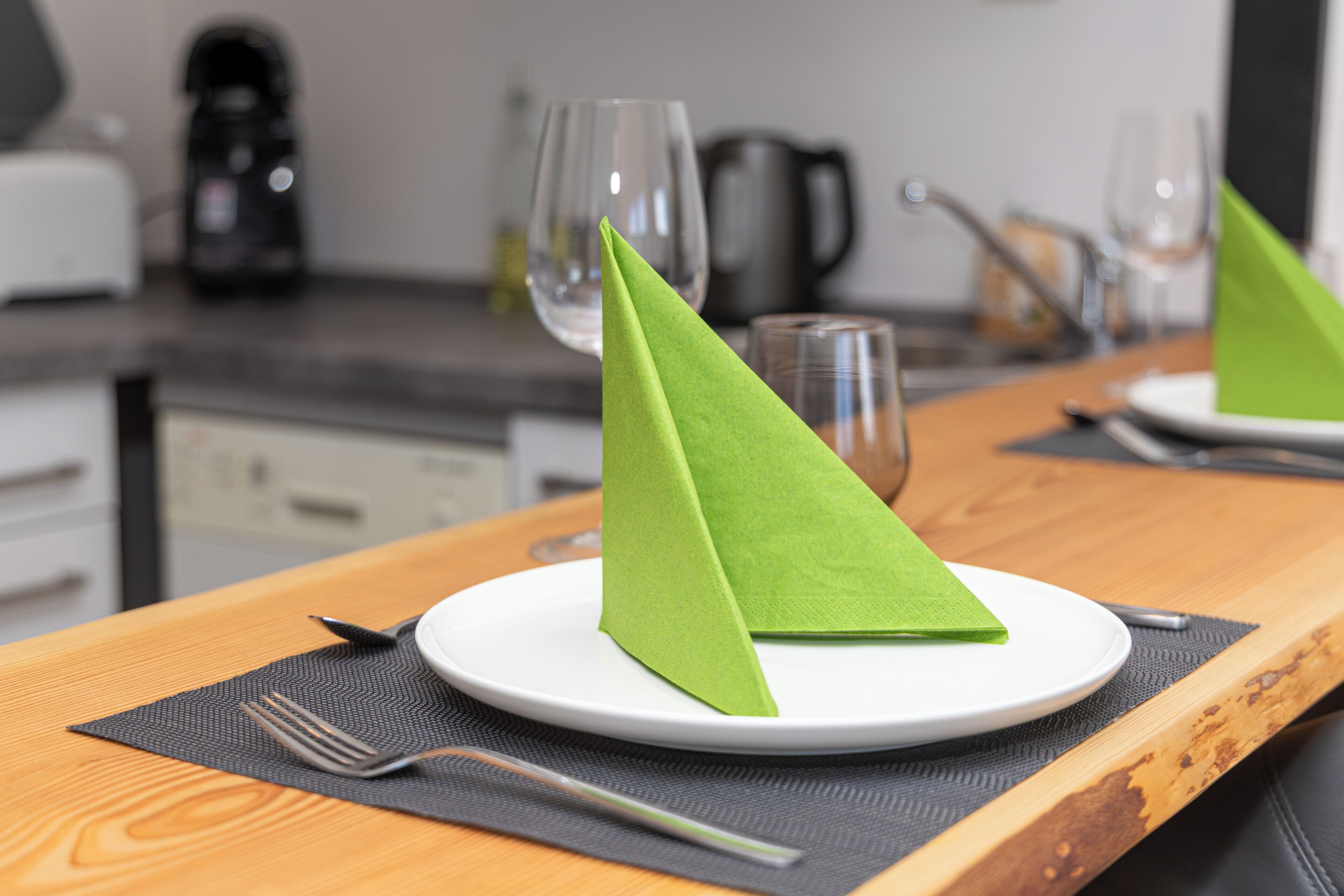 Een eettafel met een bord, een groene servet, een vork en een mes.