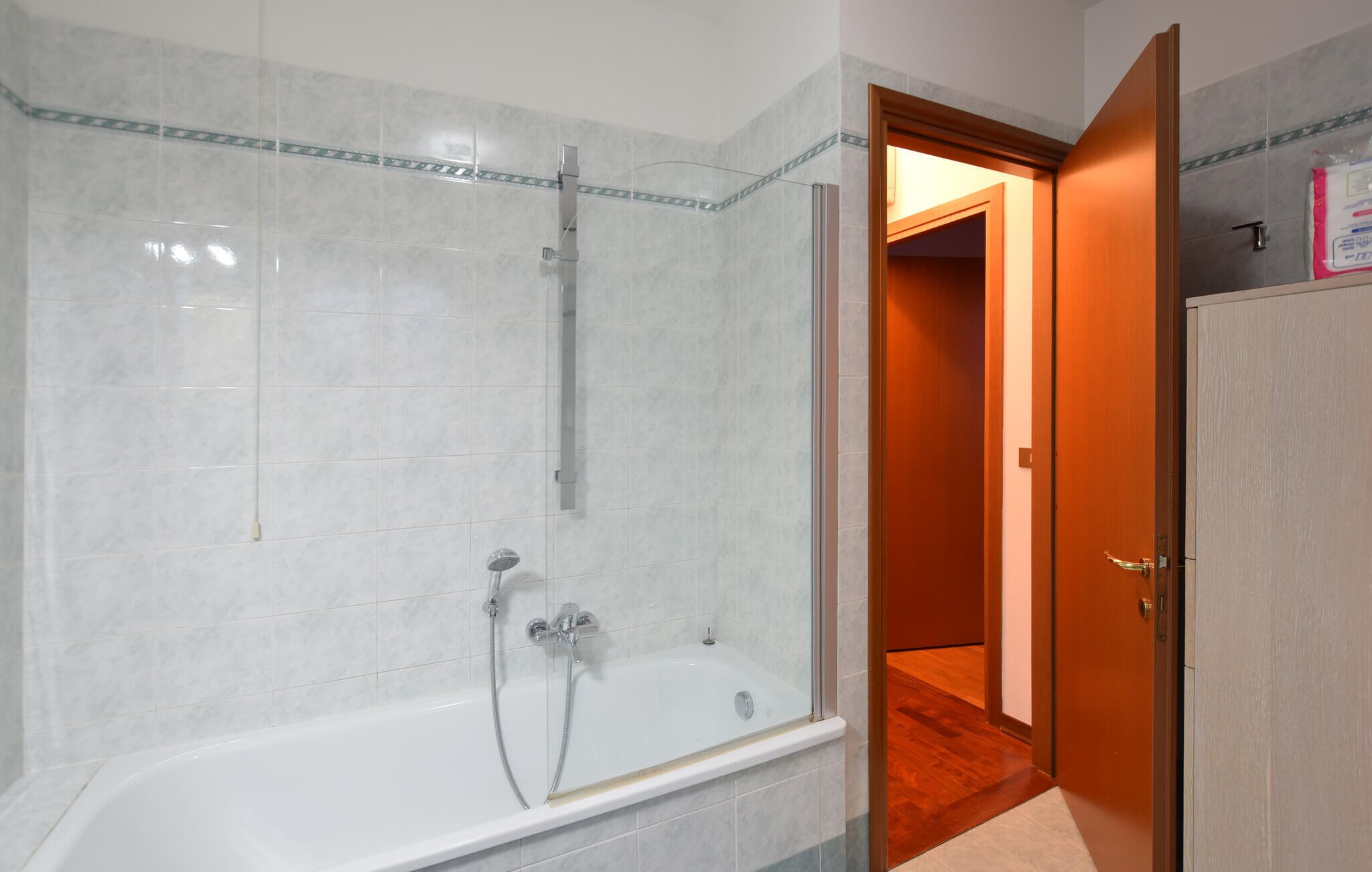 Ein Badezimmer mit Duschkabine, einer Badewanne und einer Holztür zu einem anderen Raum.