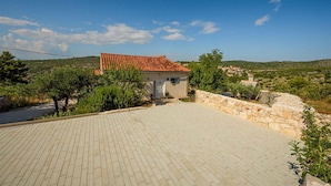 A house with a tiled roof, a paved driveway, and a stone wall. - Cozy home in Bobovisca (Bobovisca)