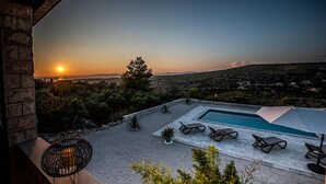 A pool area with lounge chairs and a view of the sunset over a hilly landscape. - Cozy home in Bobovisca (Bobovisca)