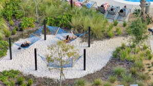 A beach area with hammocks and lounge chairs, surrounded by greenery and a pool. - Fun-Filled 5-Bedroom Home with Private Pool & Steps from Water Park! (Four Corners)