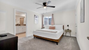 Ein Schlafzimmer mit einem Bett, einem Deckenventilator, einem Nachttisch und einem Schreibtisch.