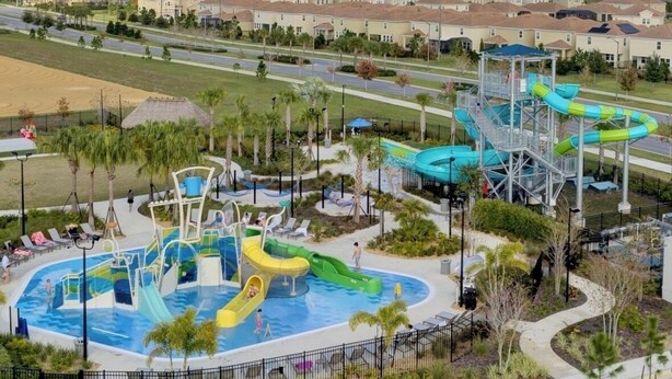Ein Wasserpark mit mehreren Wasserrutschen und einem Schwimmbecken, umgeben von einem Zaun und Palmen.