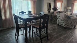 Un comedor con mesa y sillas de madera, un sofá y una mesita auxiliar con una lámpara.